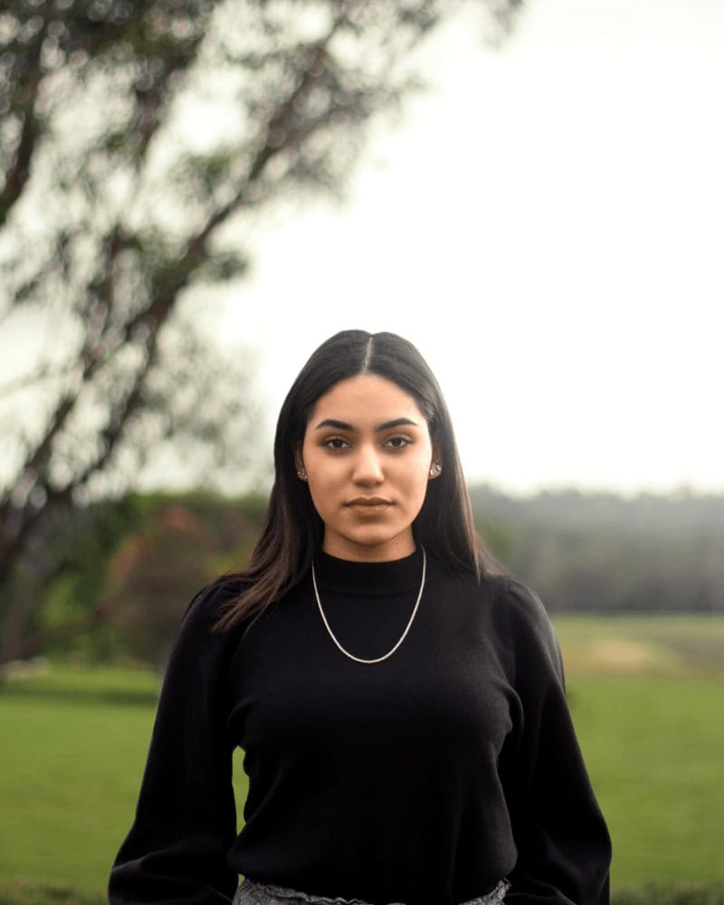 woman in black turtleneck long sleeve shirt taking outdoor headshots with nature-inspired background